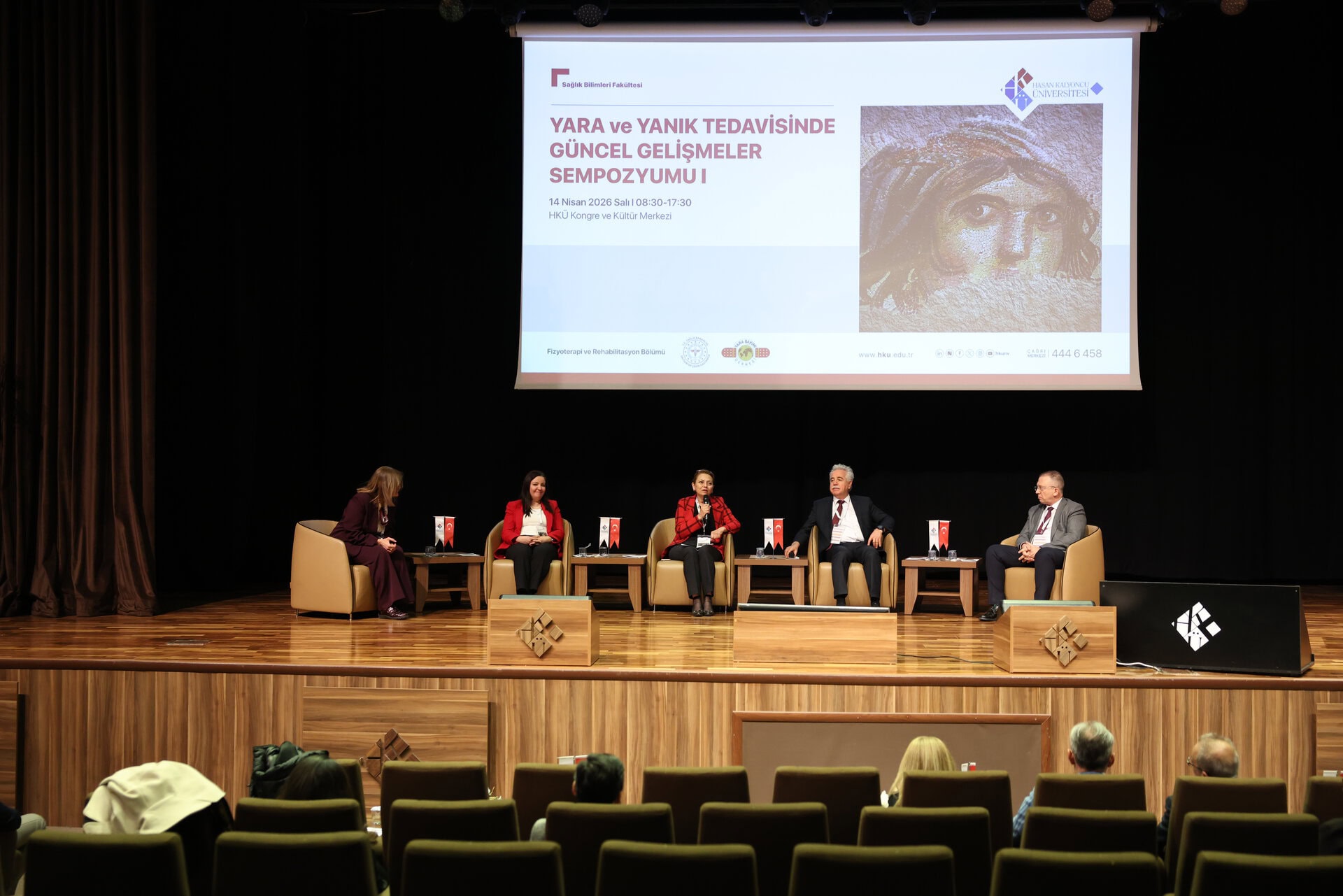 Yara ve Yanık Tedavisinde Güncel Gelişmeler Sempozyumu paneli, HKÜ Kongre ve Kültür Merkezi'nde uzmanlar sahnede.